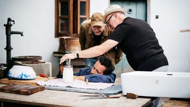 Drei Männer beobachten sehr interressiert ein Glas mit weissem Inhalt