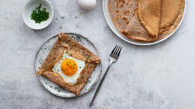 Galettes Bretonnes mit Käse und Spiegelei auf grauem Hintergrund.