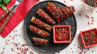 Teller mit leckerem gebratenem Fleisch und Pfeffersauce auf hellem Hintergrund.