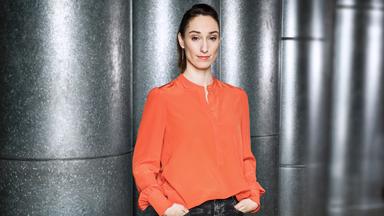 Moderatorin Vivian Perkovic steht vor Wand 