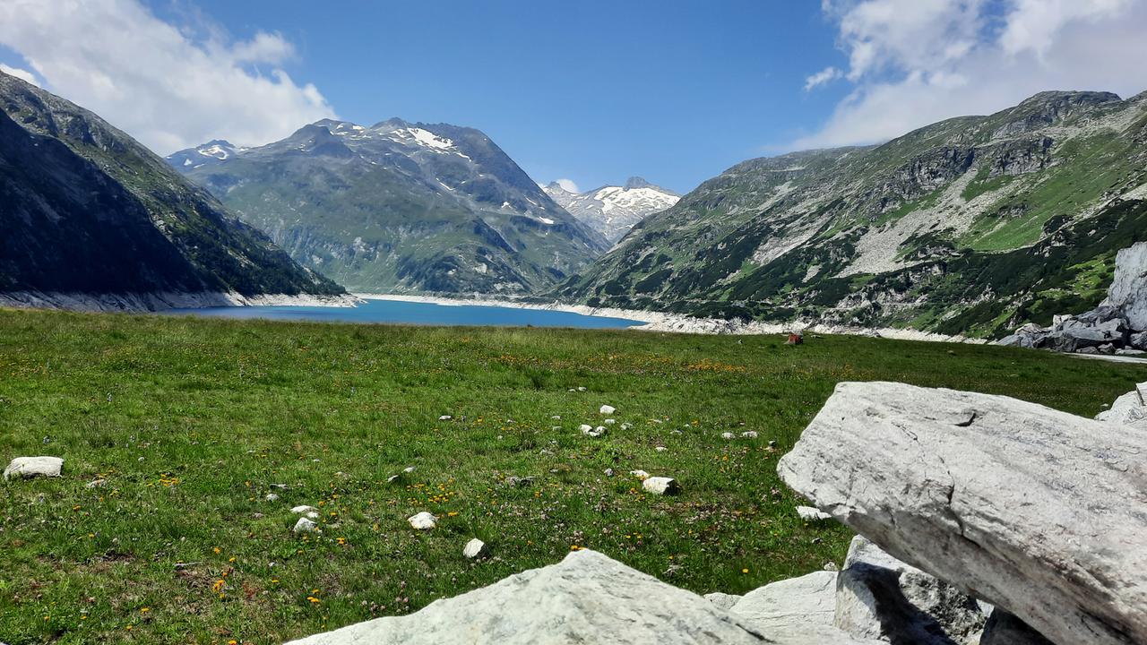 Das Bild zeigt einen Bergsee und ein Bergpanorama im Hintergrund