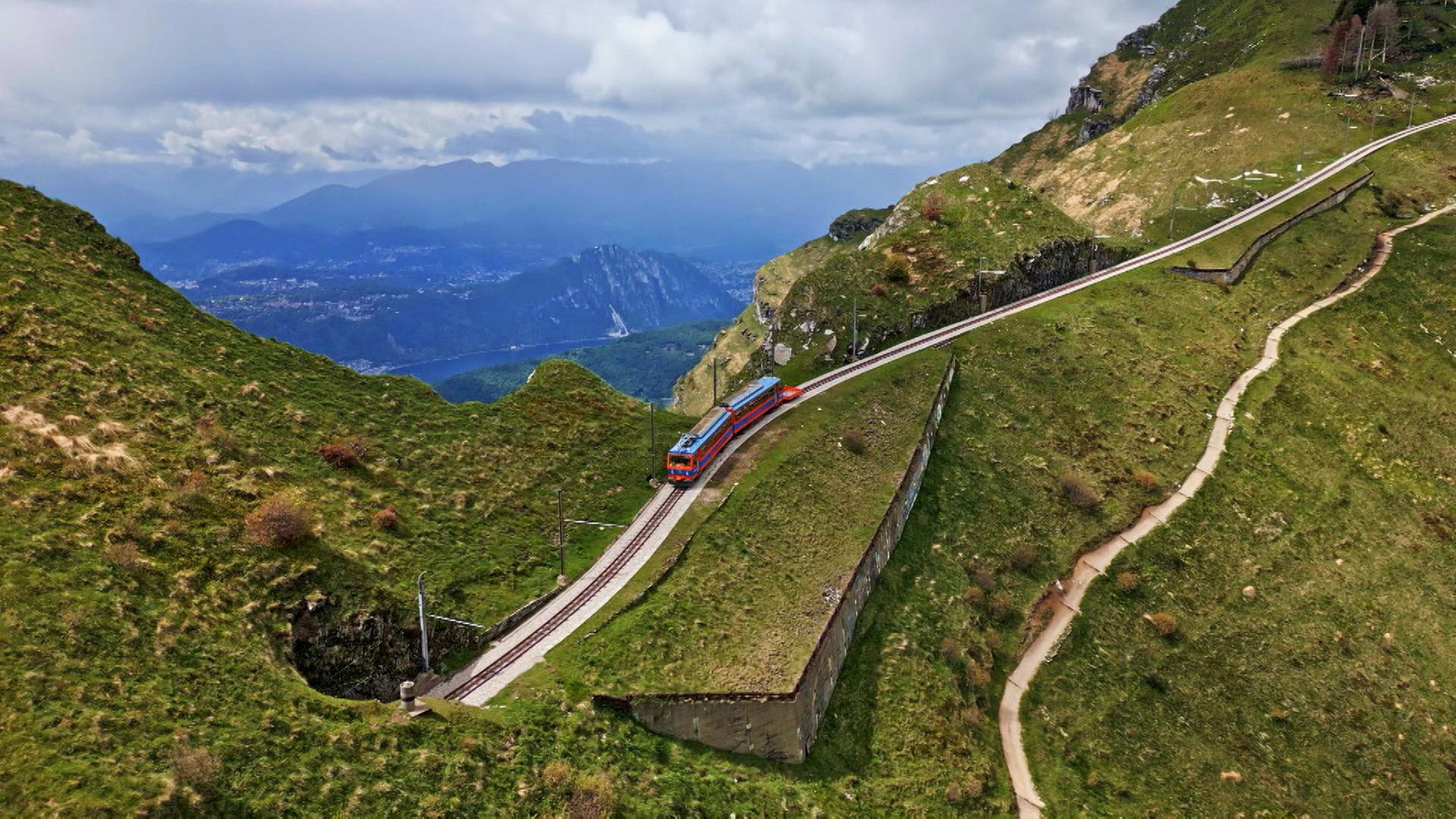 Eine rote Bergbahn unter blauem Himmel auf Bergschienen