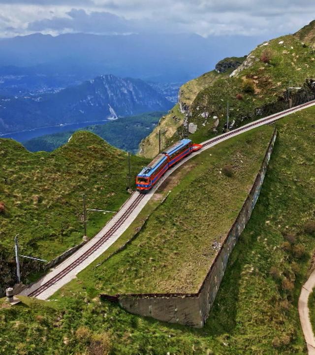 Eine rote Bergbahn unter blauem Himmel auf Bergschienen