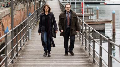 „Mord in Genua – Ein Fall für Petra Delicato: Das Zeichen“: Petra (Paola Cortellesi) und Antonio (Andrea Pennacchi) gehen am Hafen nebeneinander einen Steg entlang.
