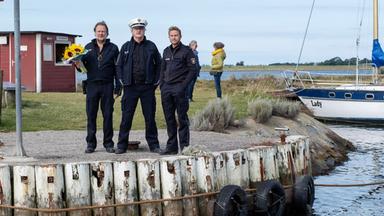 Drei Männer an einer Bootsanlegestelle.