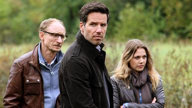 "Mordsfreunde": Kai Ostermann (Michael Schenk) und das Ermittler-Duo Oliver von Bodenstein (Tim Bergmann) und Pia Kirchhoff (Felicitas Woll) stehen auf einer Wiese.