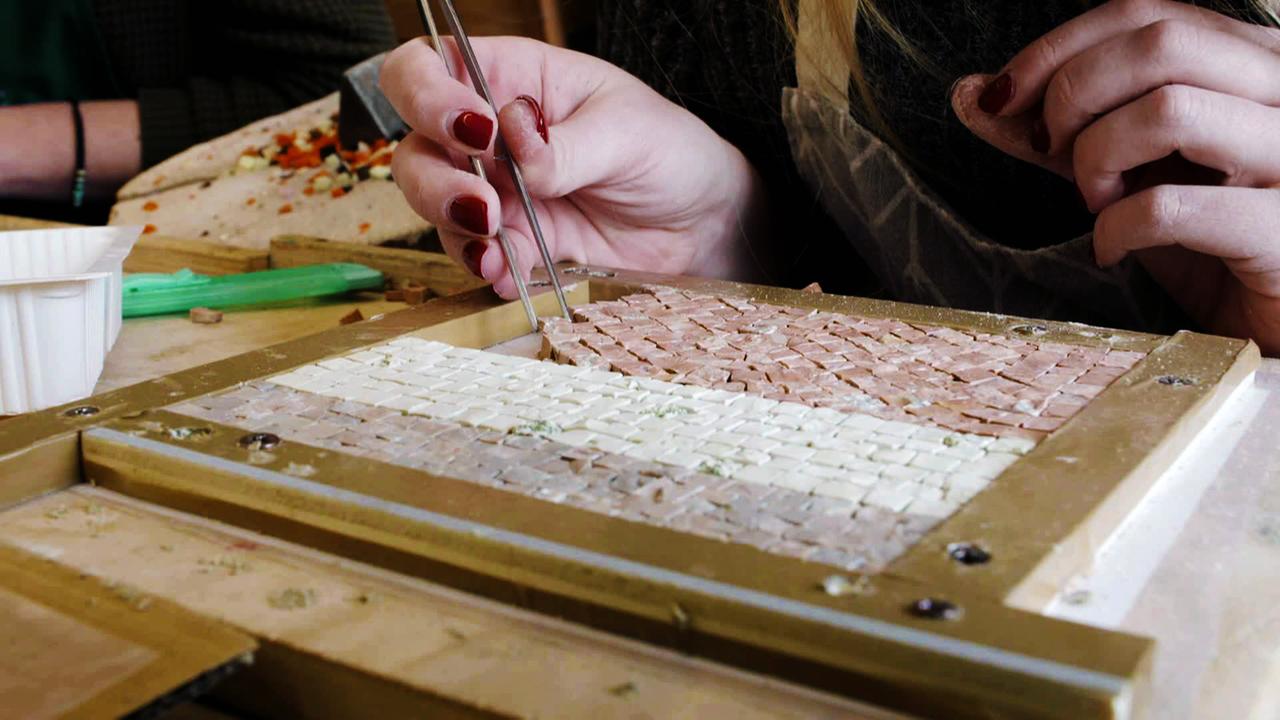 Hände mit Pinzette beim Mosaik gestalten