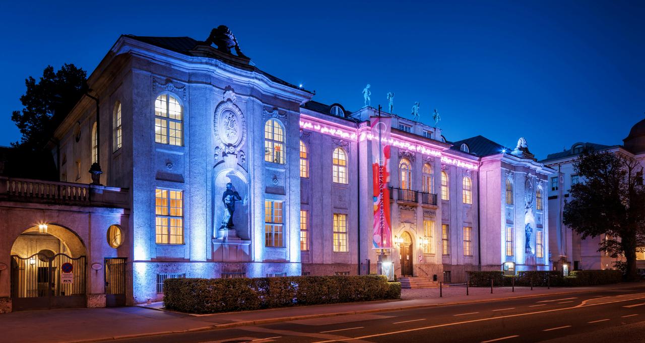 Ein in pink und blaues Licht angestrahltes altes Gebäude