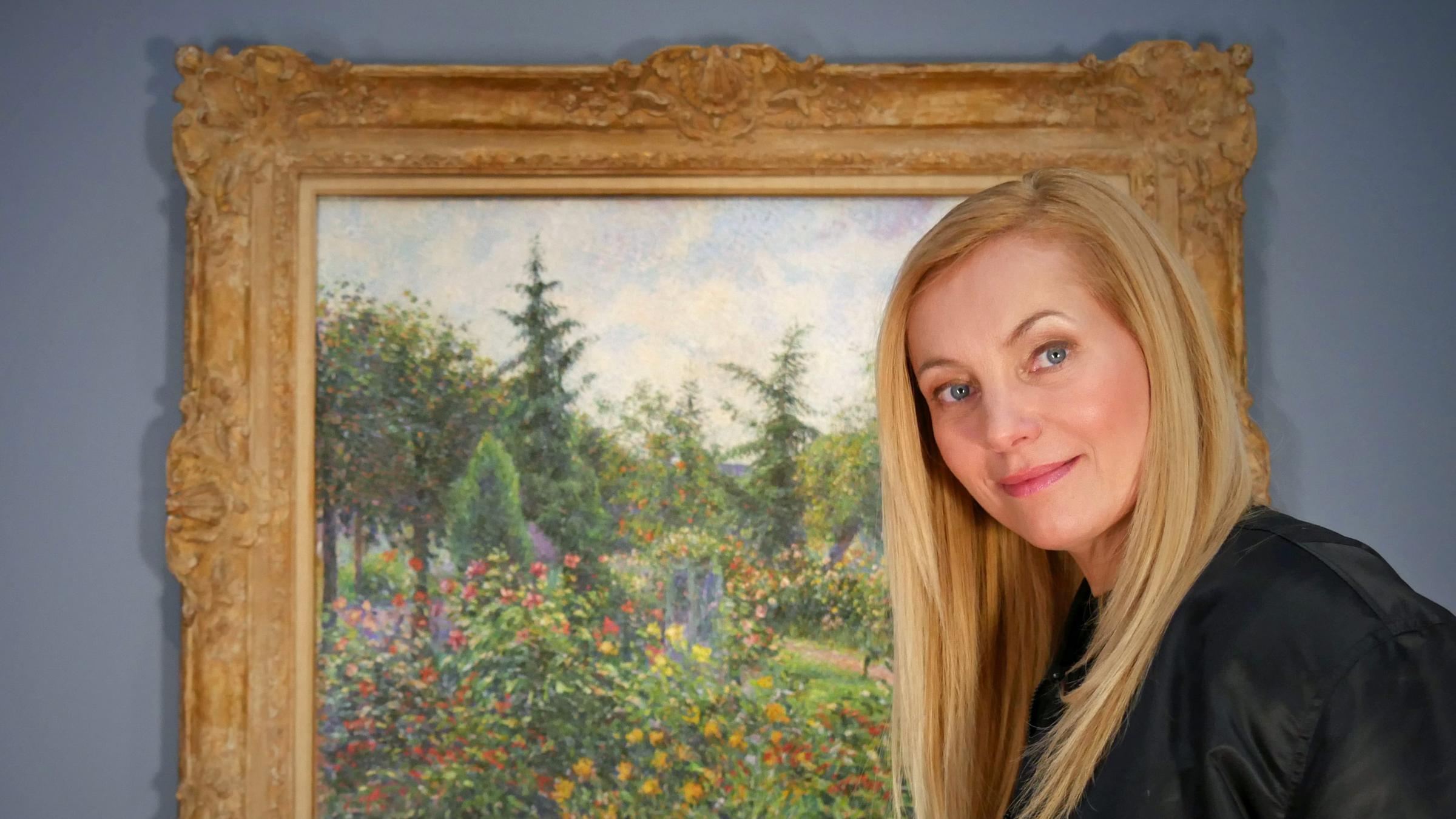 Nadja Uhl vor dem Bild eines gemalten Gartens im Museum