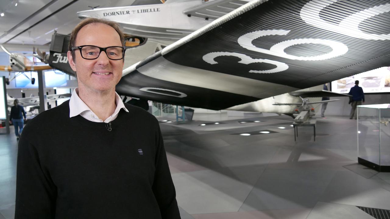Vince Ebert neben einem Flugzeug im Deutschen Museum in München