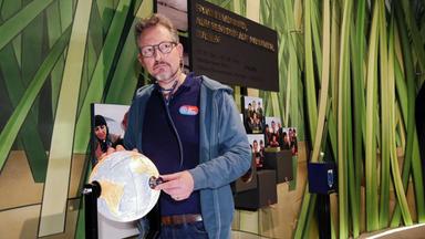 Dr. Eckart von Hirschhausen hört mit einem Stethoskop eine kleine Weltkugel ab.