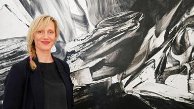 Anna Schudt steht lachend vor einem Gemälde im Museum Küppersmühle in Duisburg