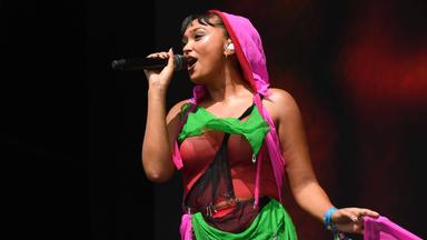 Eine Frau in einem bunten Kostüm singt in ein Mikrofon.