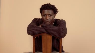 Man sieht einen Mann der auf einem Stuhl sitzen.