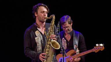 Ein Saxophonist und ein Bassist spielen auf einer Bühne.