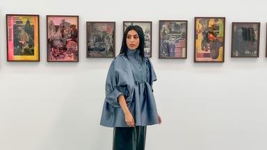 Eine dunkelhaarige Frau in eleganter Kleidung vor einer Bildergalerie. 