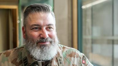 Das Portrait eines Mannes mit grauem Bart und in Tarnjacke