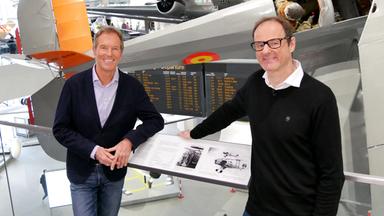 Moderator und Gast stehen vor Flugzeugen im Deutschen Museum in München