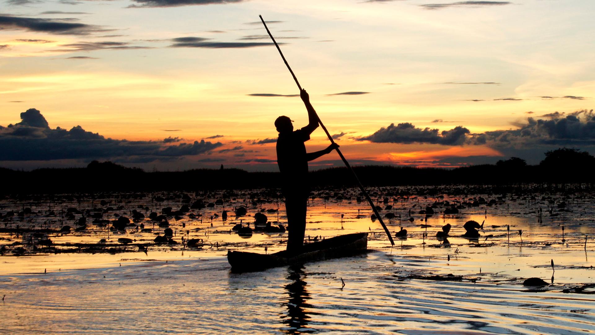 Ein Fischer in den Bangweulusümpfen Sambias in der Abenddämmerung.