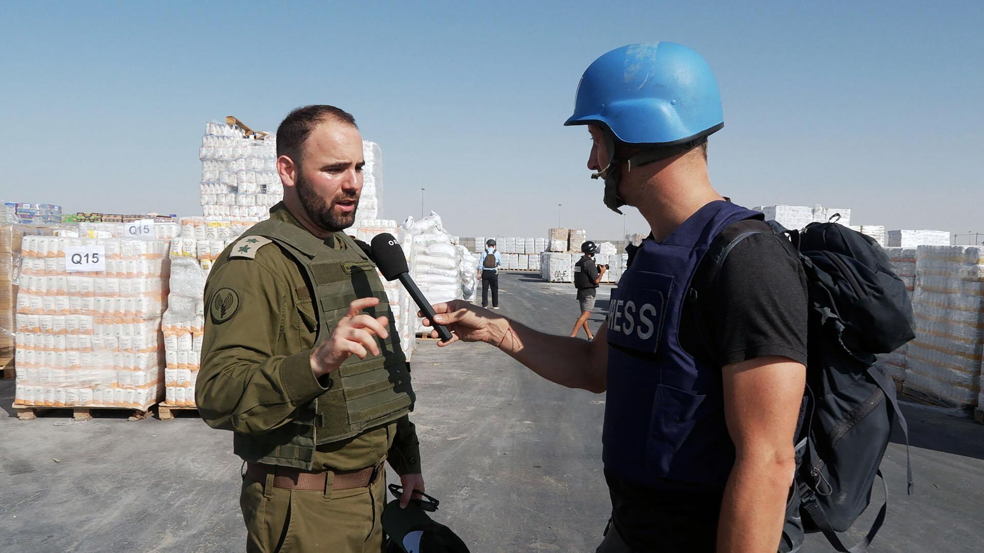 Ein Pressevertreter spricht mit einem Mann in olivgrüner Kleidung 