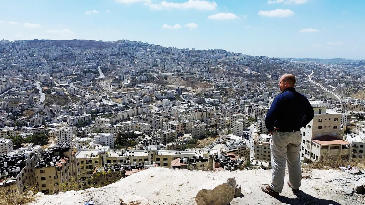 Ein Mann blickt auf die Stadt zu seinen Füssen