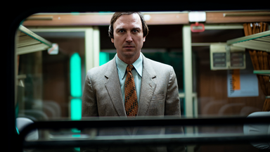 Franz Walter (Lars Eidinger) schaut frontal durch das Fenster eines Zuges