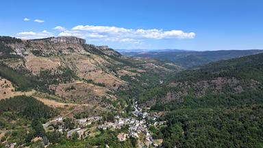 Luftaufnahme eines weitläufigen Tals. Am unteren Bildrand sind Häuser und Straßen eines Dorfes zu erkennen. Dahinter eine karge Hügellandschaft.
