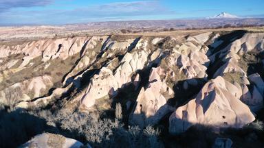 Hellgraue Felswände an einer Talseite - im Hintergrund ein weißer Berg.