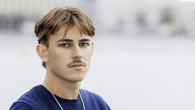 Porträtfoto eines jungen Mannes mit Oberlippenbart.