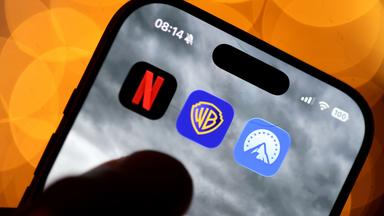Auf einem Handy sind die Apps von Netflix, Paramount und Warner Bros. nebeneinander zu sehen.