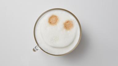 eine Tasse Cappuchino von oben mit einem Smiley im Milchschaum