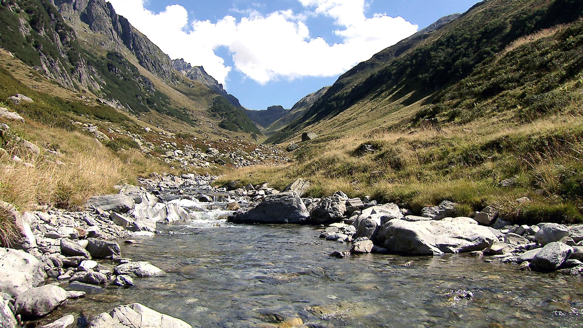 Gebirgsbach mit großen Steinen vom Wasser aus gesehen