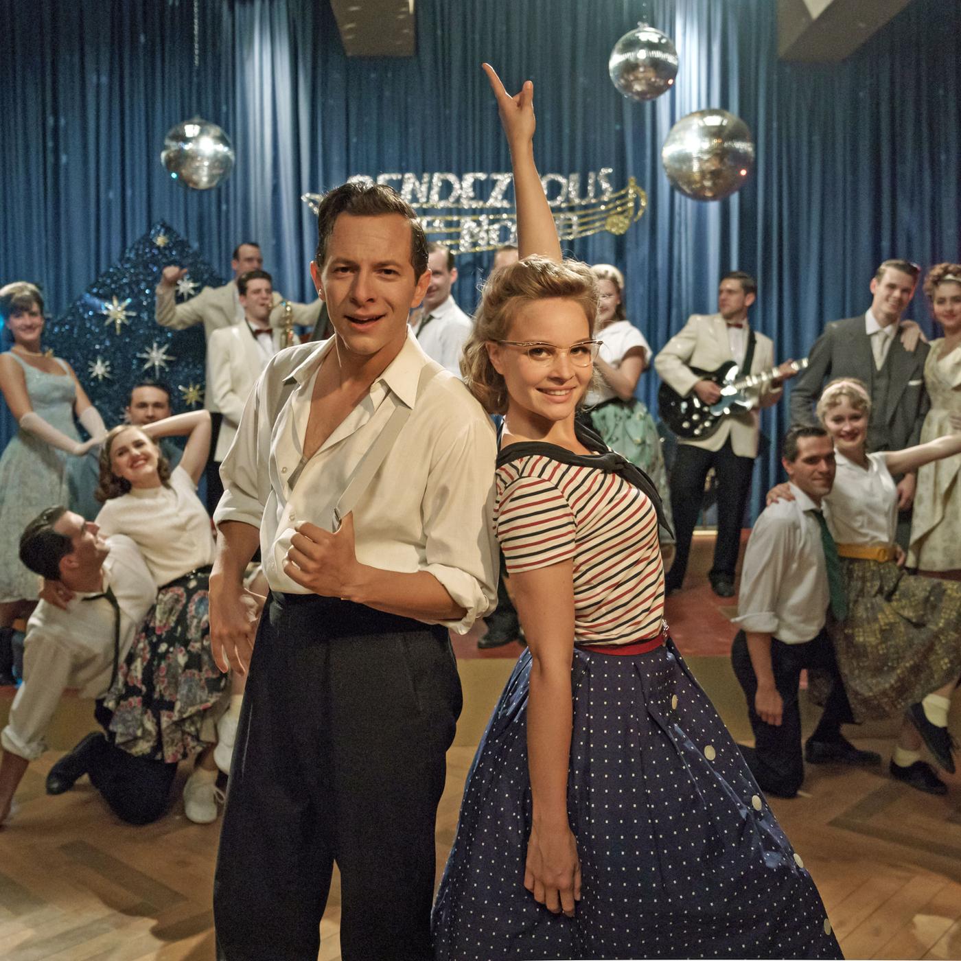 "Ku'damm 59": Monika Schöllack (Sonja Gerhardt, m.r.) und Freddy Donath (Trystan Pütter, m.l.) stehen im Vordergrund und posieren für die Kamera. Im Hintergrund posieren weitere Darsteller der Fernsehshow "Rendezvous nach Noten".