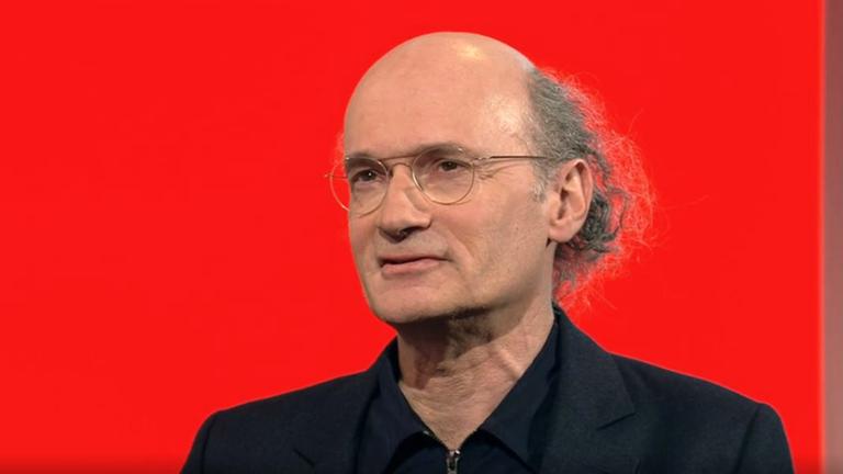 Mann mit Glatze und dünner Metall-Brille.