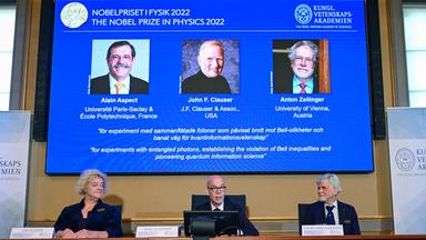 Bekanntgabe der Preisträger des Nobelpreises für Physik - die Preisträger sind auf einem großen Screen zu sehen.
