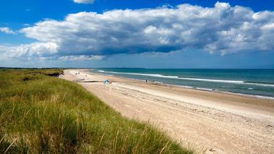 Blick auf einen Strand, auf der einen Seite die Nordsee, auf der anderen Seite Dünen
