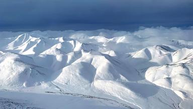 Schneebedecktes Gebirge aus Helikopter-Sicht.