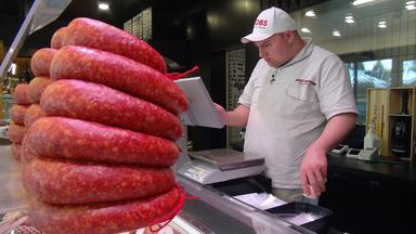 Ein Mann einer Metzgerwaage hinter einer Theke.