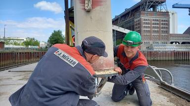 Zwei Männer arbeiten auf einem Schiff.