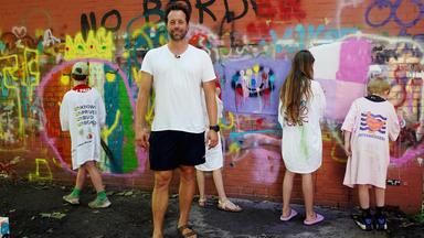 Maik Reichelt mit vier Kindern, die mit dem Gesicht an eine bunte Wand schauen