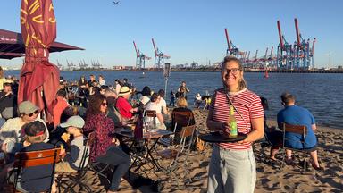 Eine Frau steht mit Tablett bei der Strandperle in Hamburg-Övelgönne
