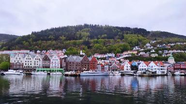 Blick über einen See, an dessen Ufer Schiffe vor historischen Gebäuden liegen.