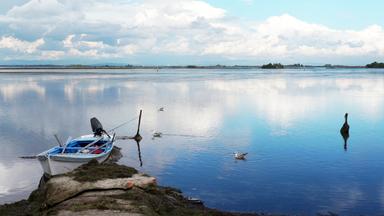 ein boot liegt am wasser vor einem blauen himmel