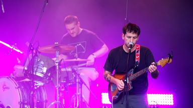 Ein Mann an der Gitarre und ein weiterer Mann am Schlagzeug auf einer Bühne.