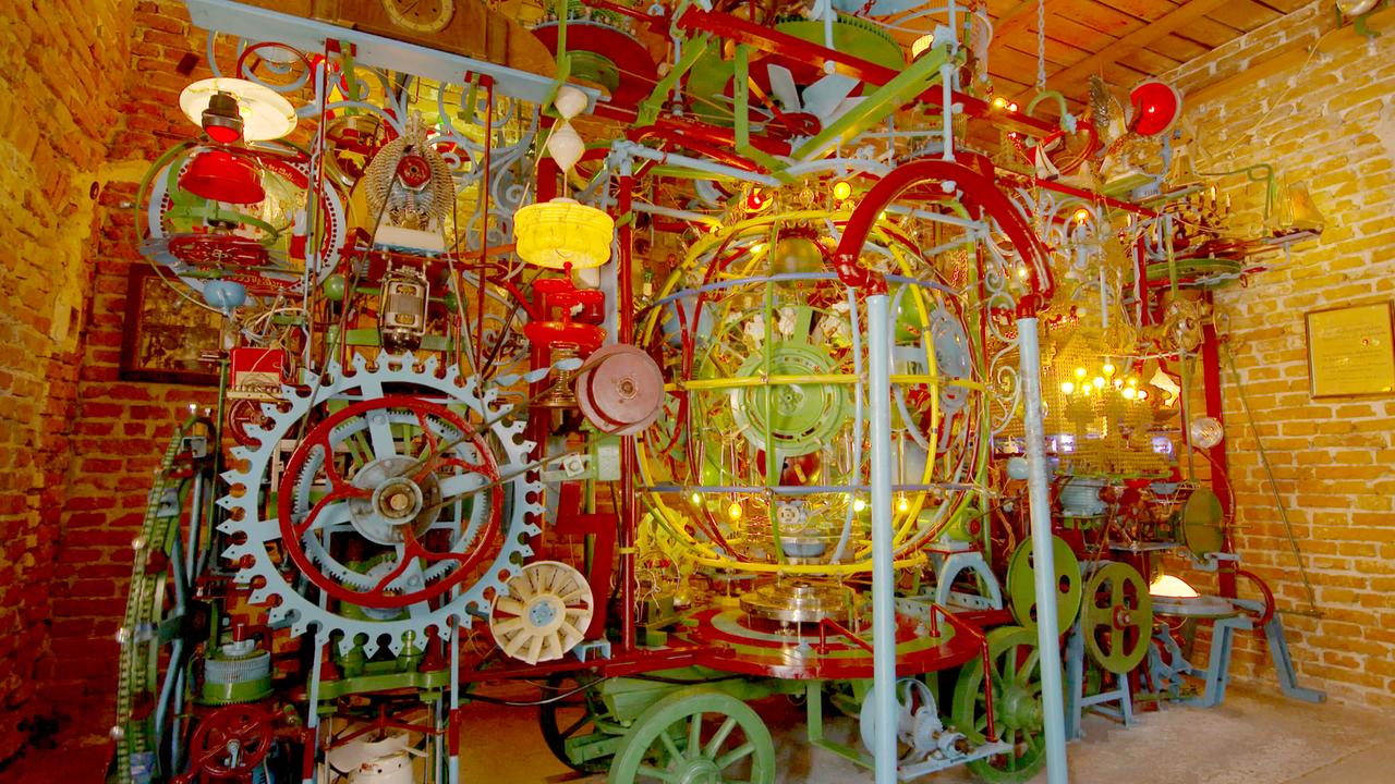 Die Weltmaschine.  Eine Rauminstallation mit bunten ineinandern wirkenden Zahnrädern, Hebel...