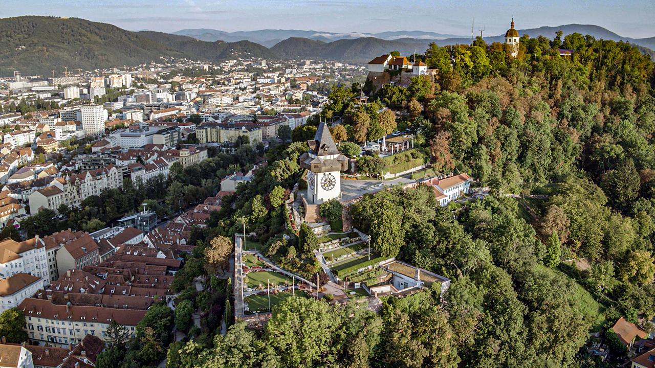 Stadt aus der Vogelperspektive, im Vordergrund ein Turm auf einem Berg