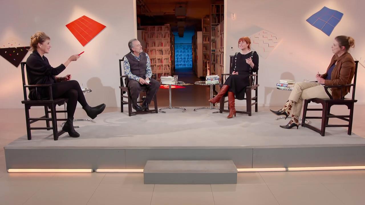 Auf einem Podest sitzen das Expertinnen-Team und Gert Scobel auf dunklen Holtstühlen und diskutieren (v.l.n.r.: Barbara Vinken, Gert Scobel, Katrin Schumacher, Sandra Kegel).