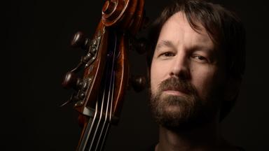 Der Kontrabassist Caminero, mit Hals vom Kontrabass Kopf groß