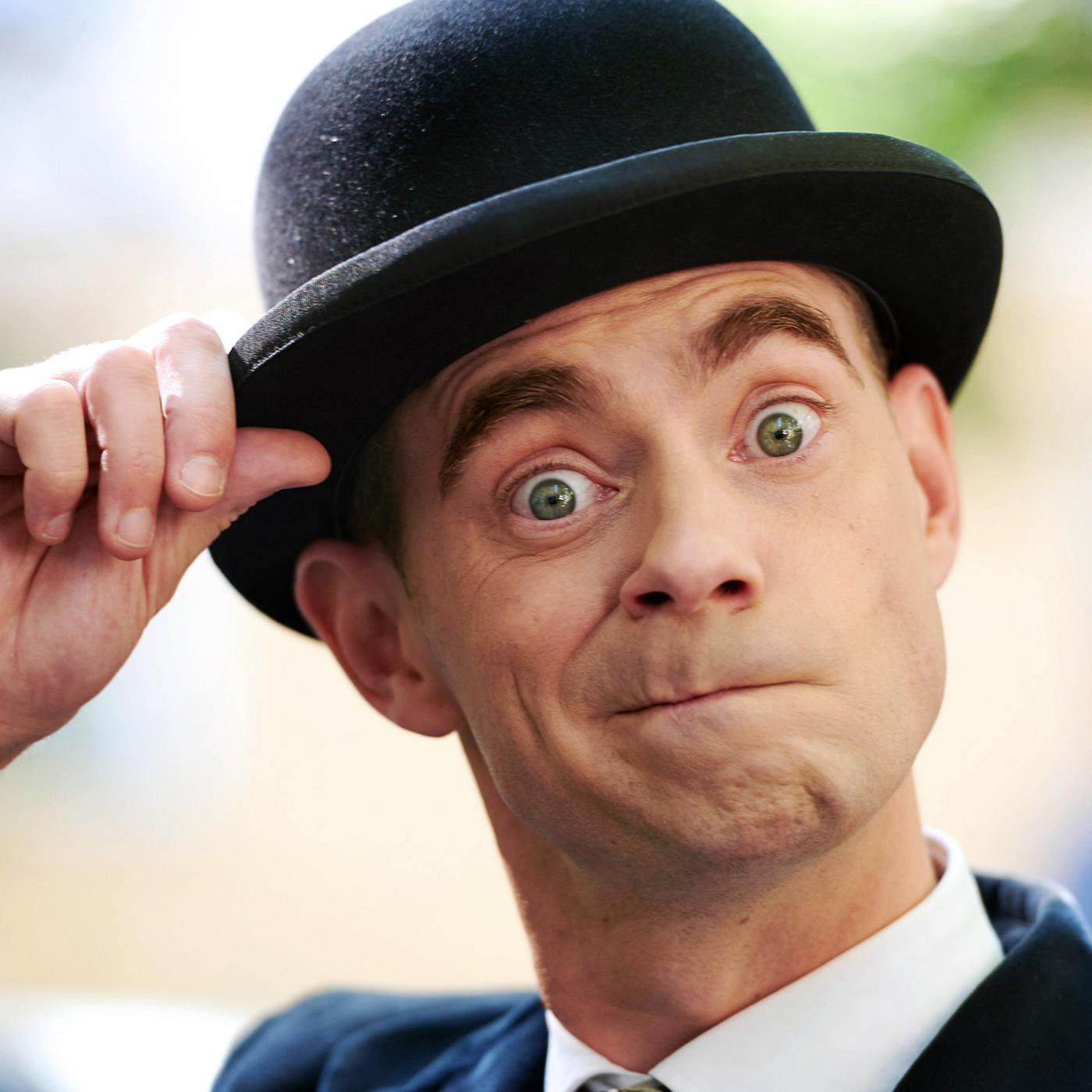 Pan Tau (Matt Edwards) macht eine lustige Grimasse und fasst sich dabei an seinen Hut