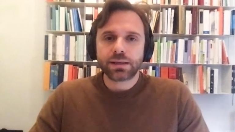 Gesprächsgast per Spkype-Interview: Mann frontal vor Bücherregal mit Kopfhörern